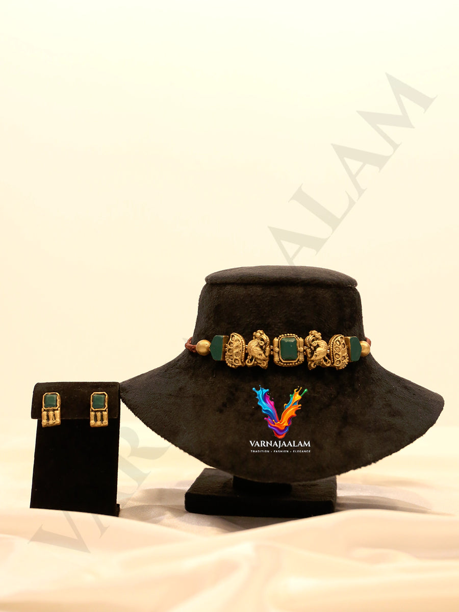 Handcrafted terracotta choker necklace set featuring antique gold peacock motifs, square dark green stones, and matching square stud earrings