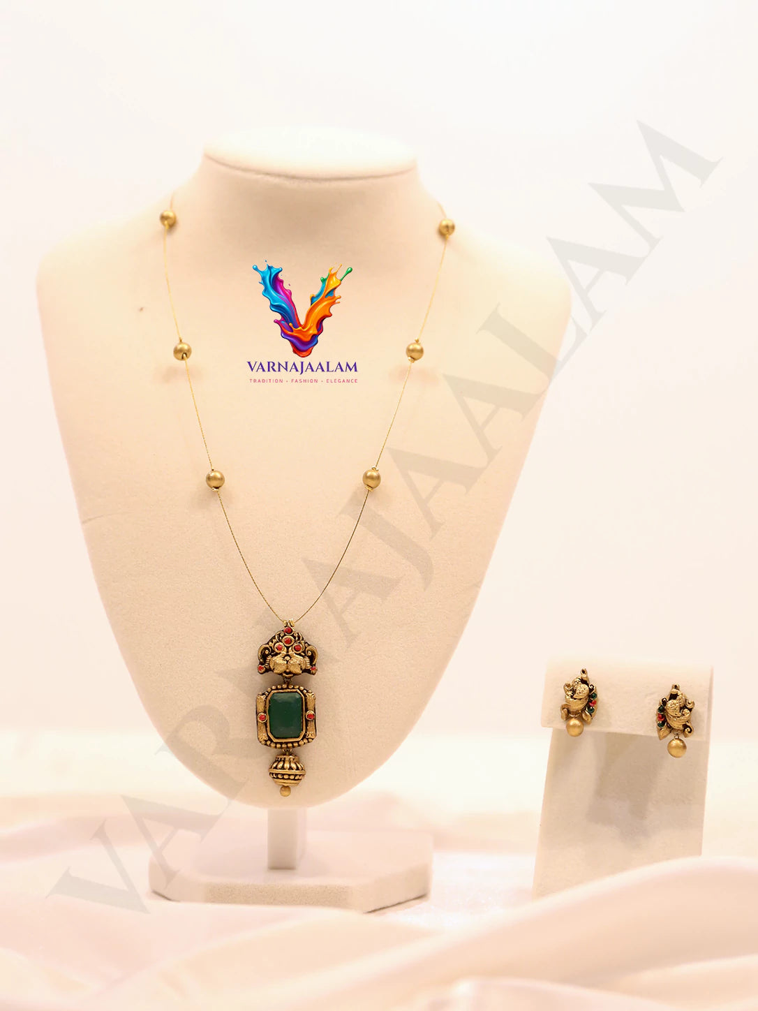 Minimalist invisible wire chain necklace with an antique gold terracotta pendant, rectangular emerald green stone, and matching peacock earrings