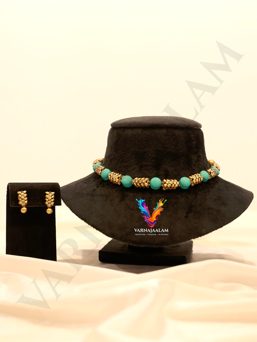 Handcrafted terracotta choker necklace with smooth turquoise round beads, textured antique gold spacer cylinders, and matching gold drop stud earrings