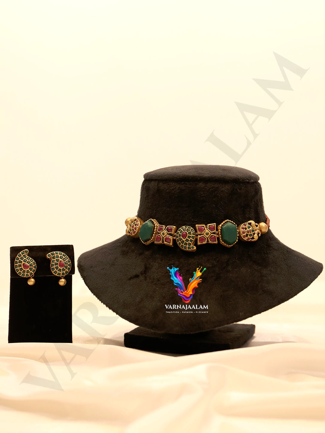 Handcrafted terracotta choker necklace featuring a center gold mango paisley motif, flanked by red square mosaic tiles, emerald green stones, outer peacock accents, and matching paisley stud earrings