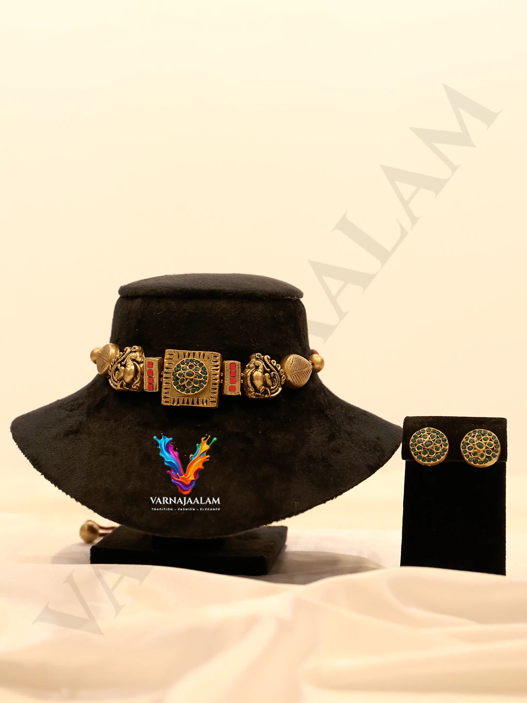 Handcrafted terracotta choker necklace featuring a square central panel with a green beaded circle, flanked by red rectangular accents, carved antique gold peacocks, leaf-textured beads, and matching round green stud earrings