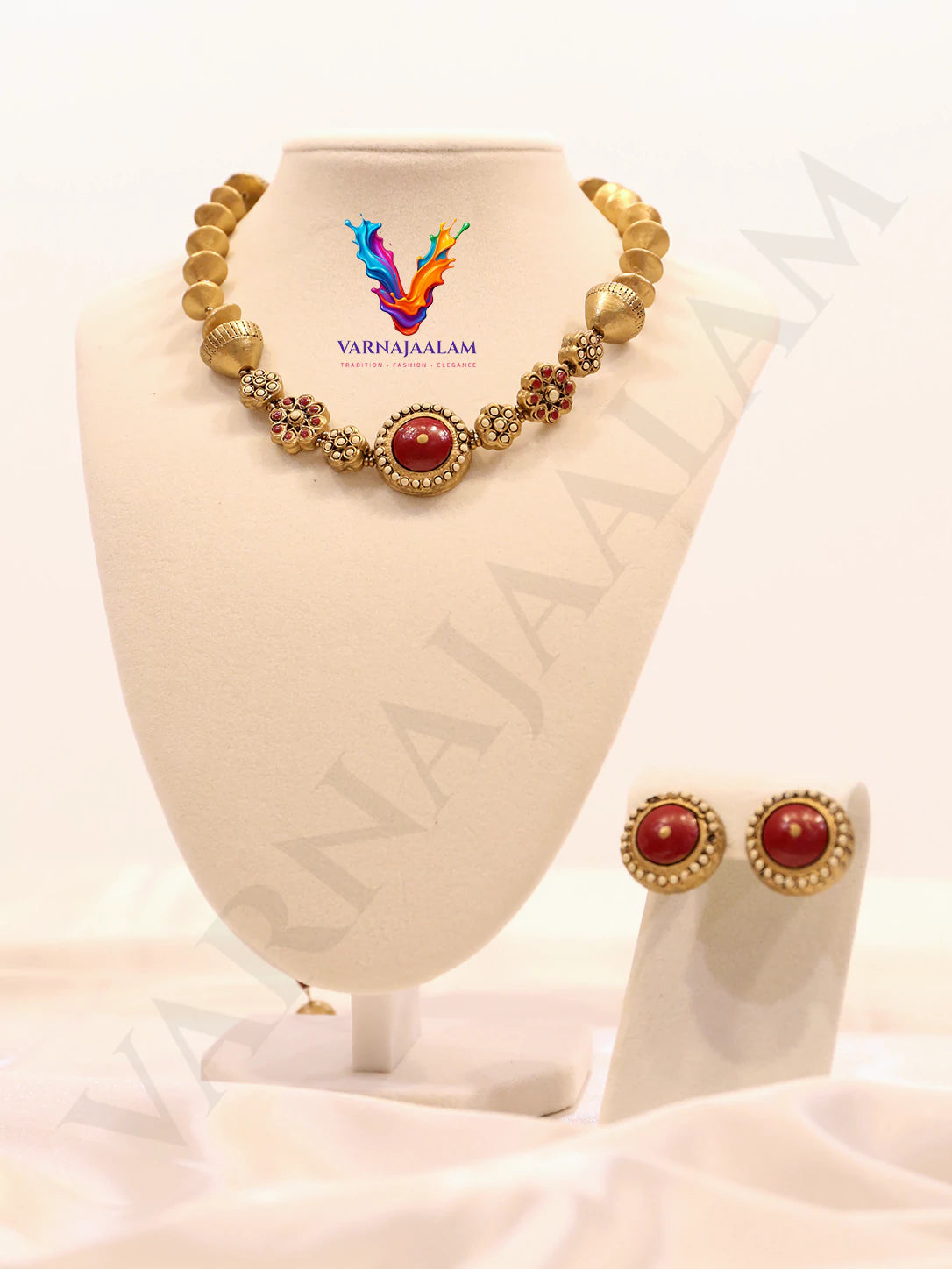 Handcrafted terracotta necklace featuring a central circular red medallion framed in antique gold, flanked by red flower motifs, textured gold beads, saucer beads, and matching red circular stud earrings