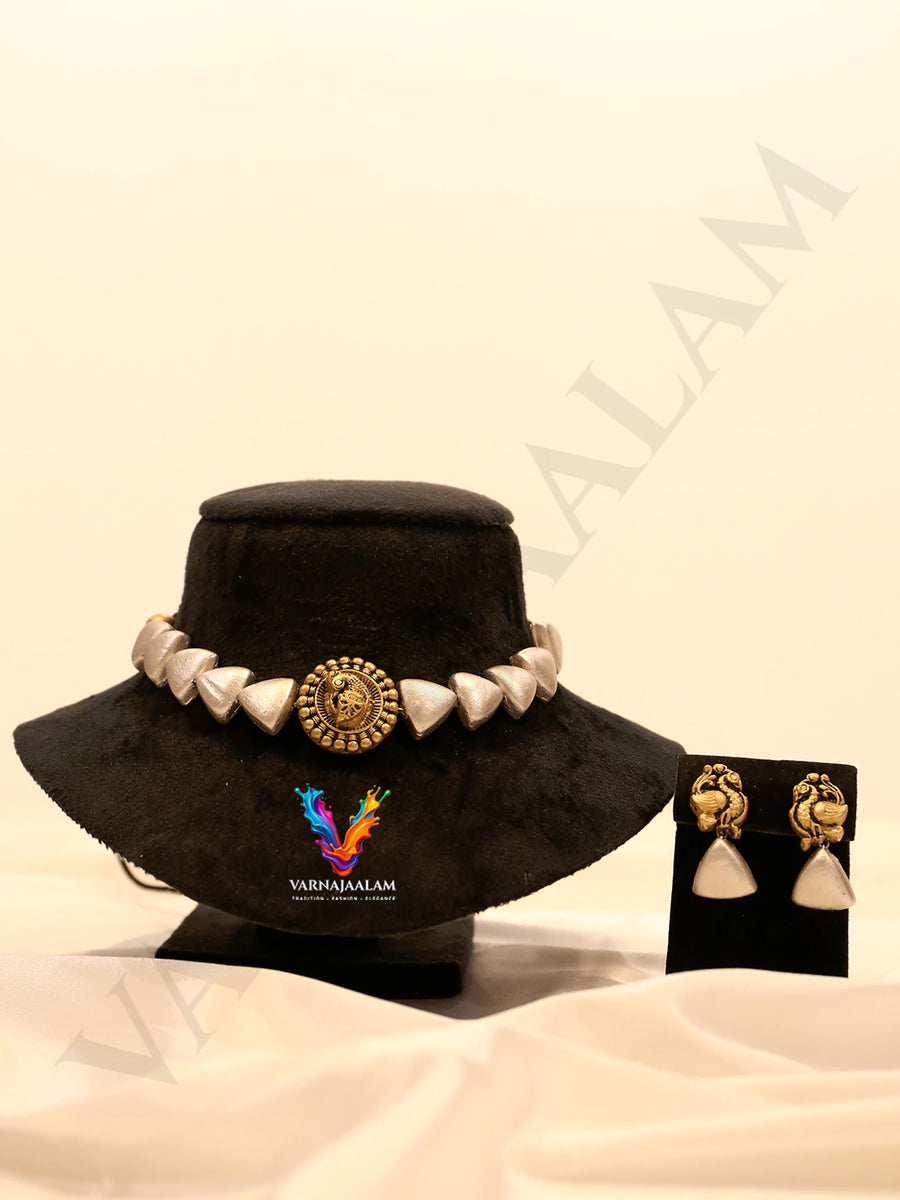 Terracotta choker with silver triangular beads, a central antique gold peacock medallion, and matching peacock drop earrings