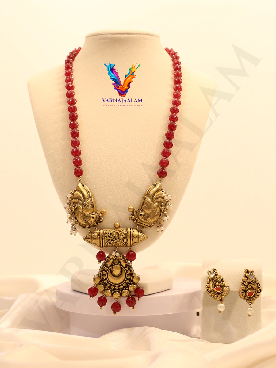 Terracotta red bead mala with gold peacock side motifs, center pendant, and matching earrings