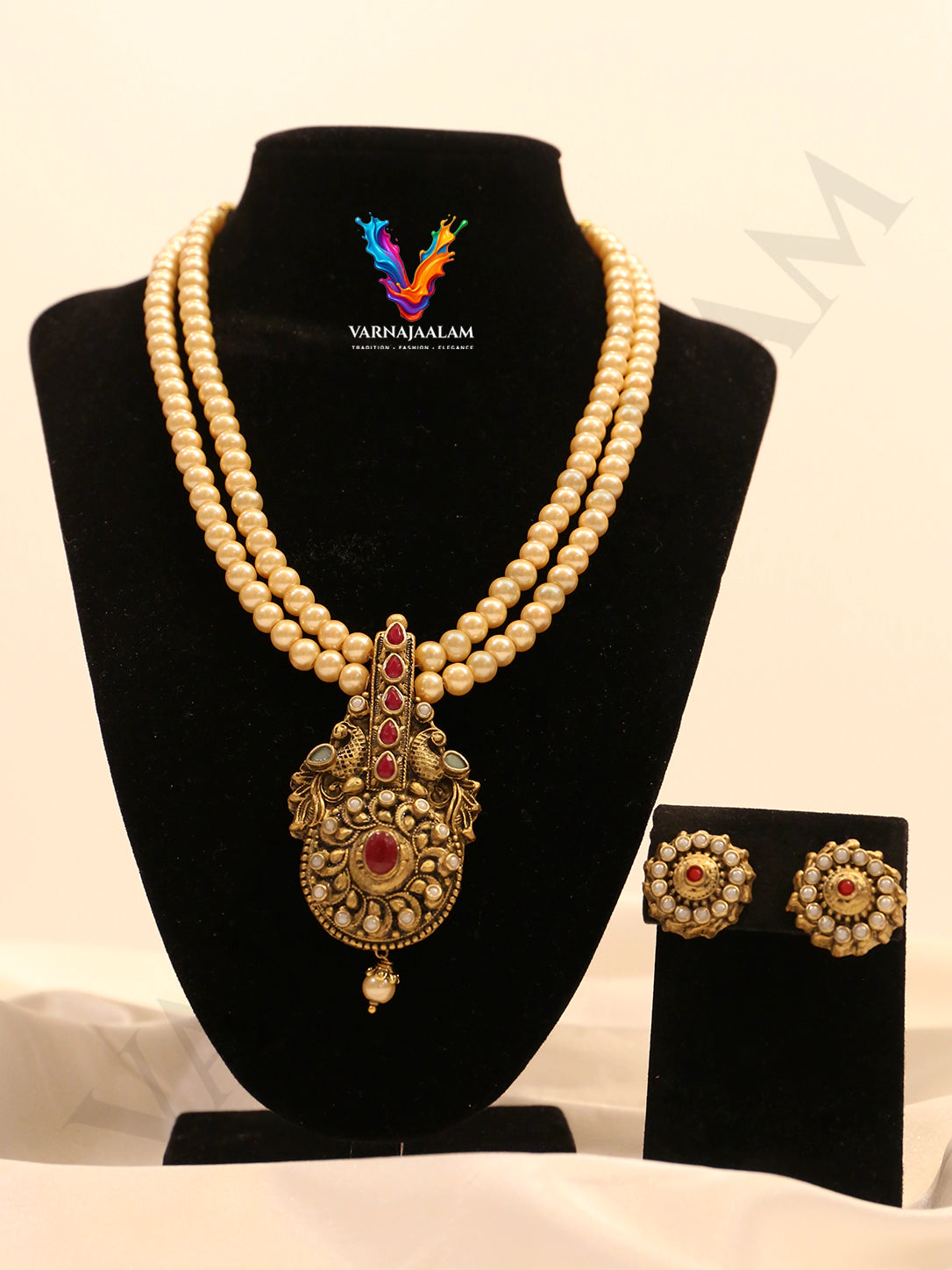 Terracotta double-strand pearl mala with gold ruby-accented peacock medallion pendant and circular stud earrings
