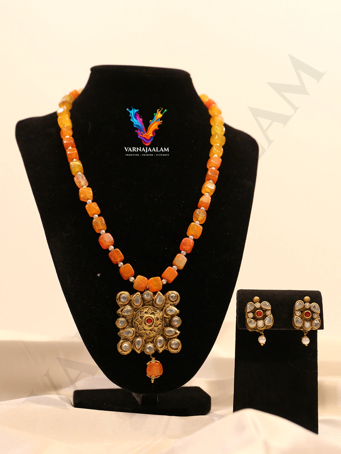 Terracotta long mala with fiery orange tumbled beads, antique gold Kundan stone-studded square medallion pendant, and matching earrings