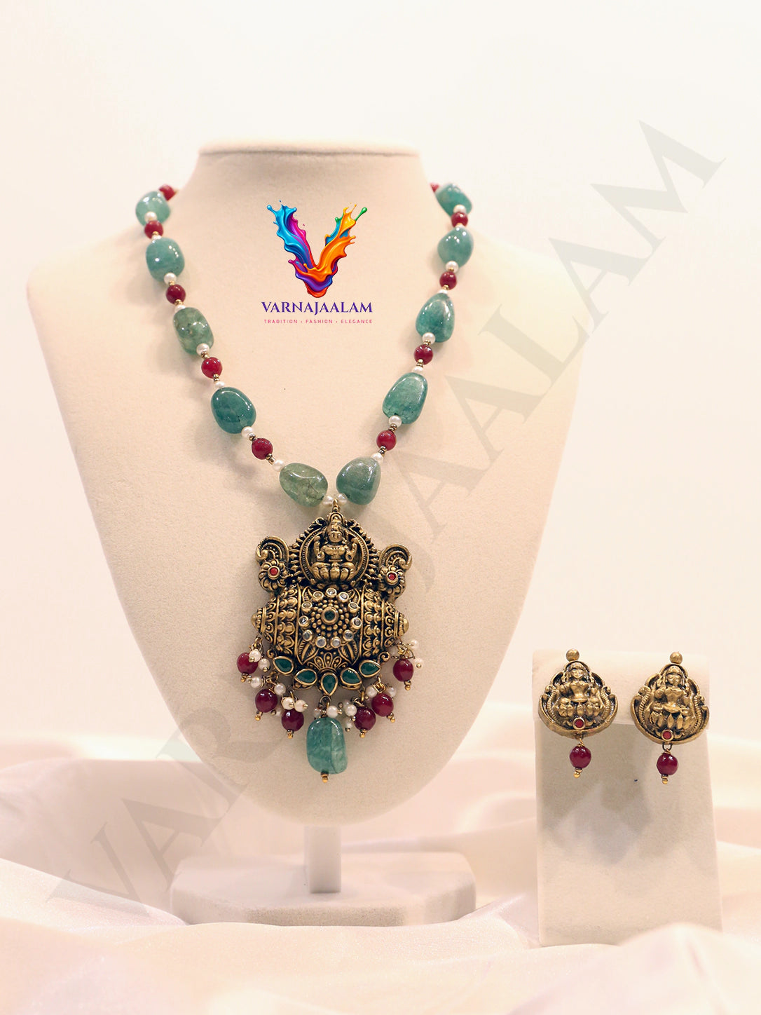 Terracotta long mala with green tumble beads and ruby red spacer beads, featuring an antique Lakshmi temple pendant with gemstone drops and matching Lakshmi earrings.