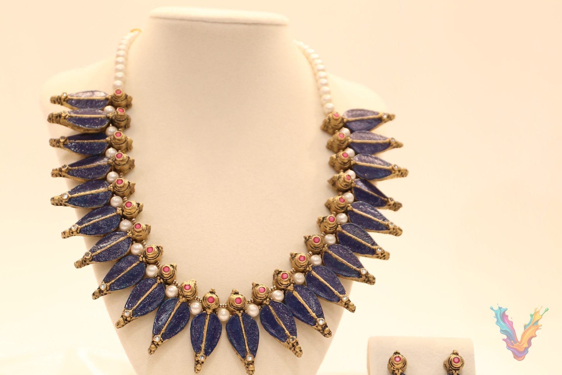 A blue and gold terracotta necklace with matching earrings displayed on a jewellery bust